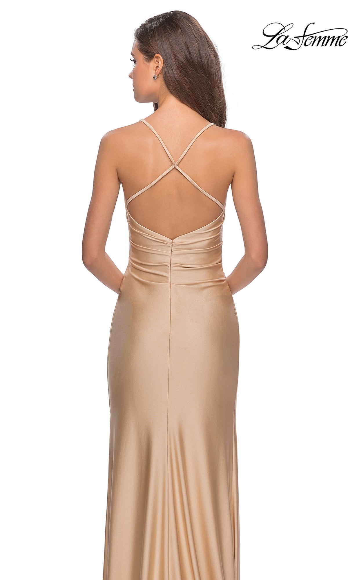 Woman modeling the La Femme Open-Back Long V-Neck Prom Dress 28206 in champagne satin, featuring a ruched back and crisscross spaghetti straps, standing against a white background.